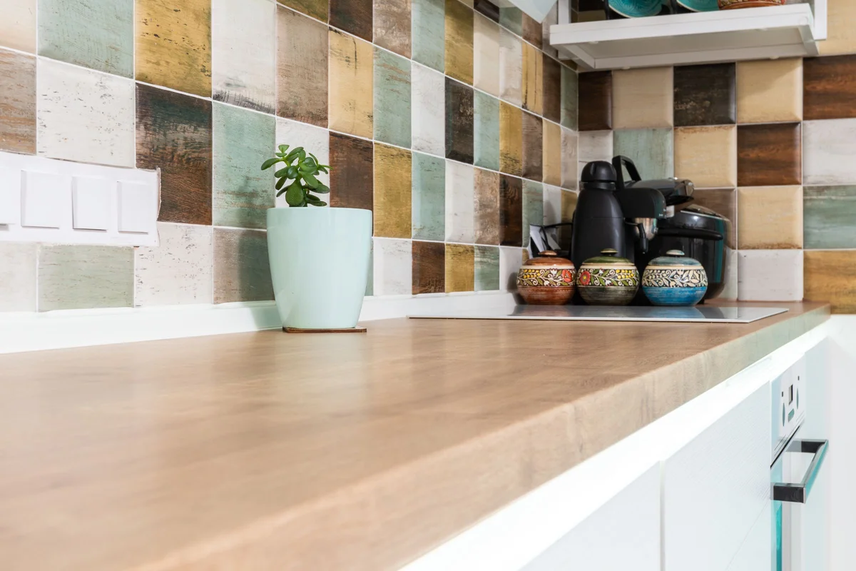 Muted colourful splashback tiles above a timber kitchen benchtop