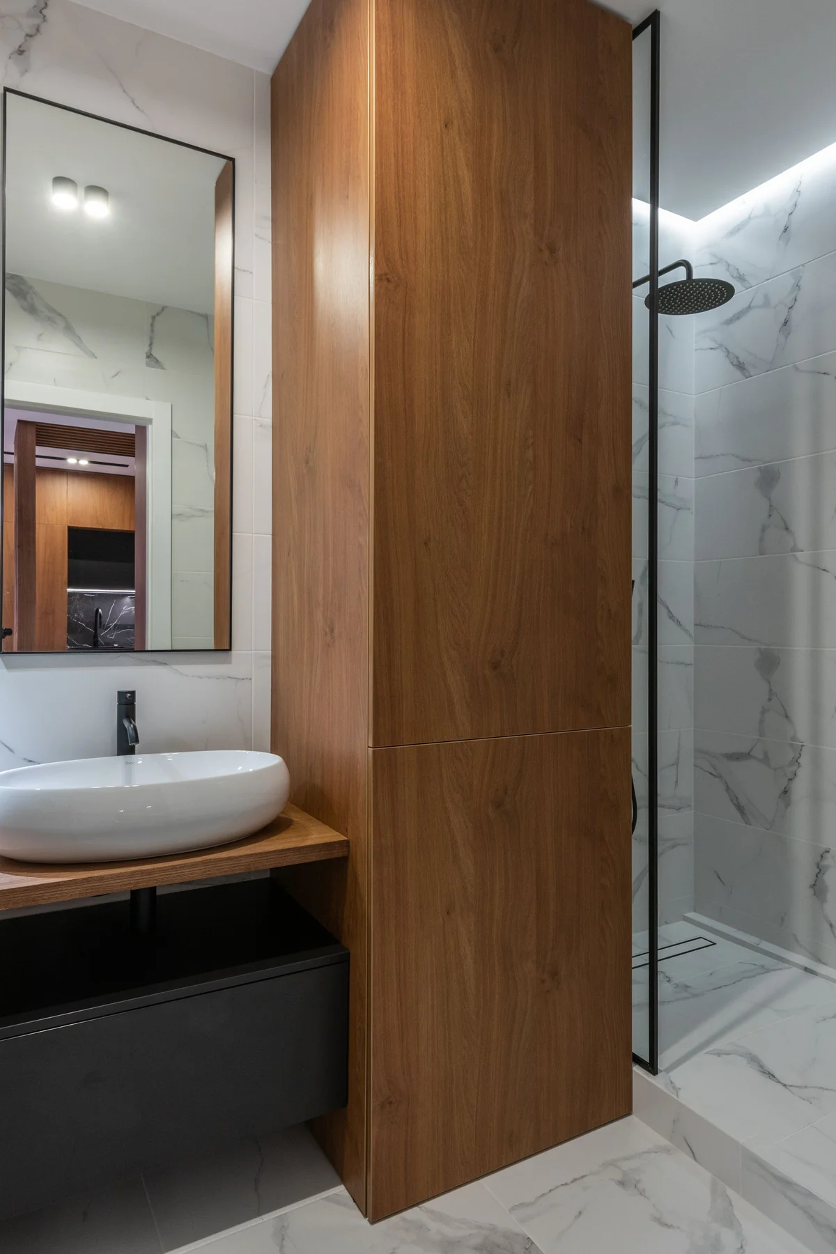 Detail of tiled wall, timber cabinetry and a basin