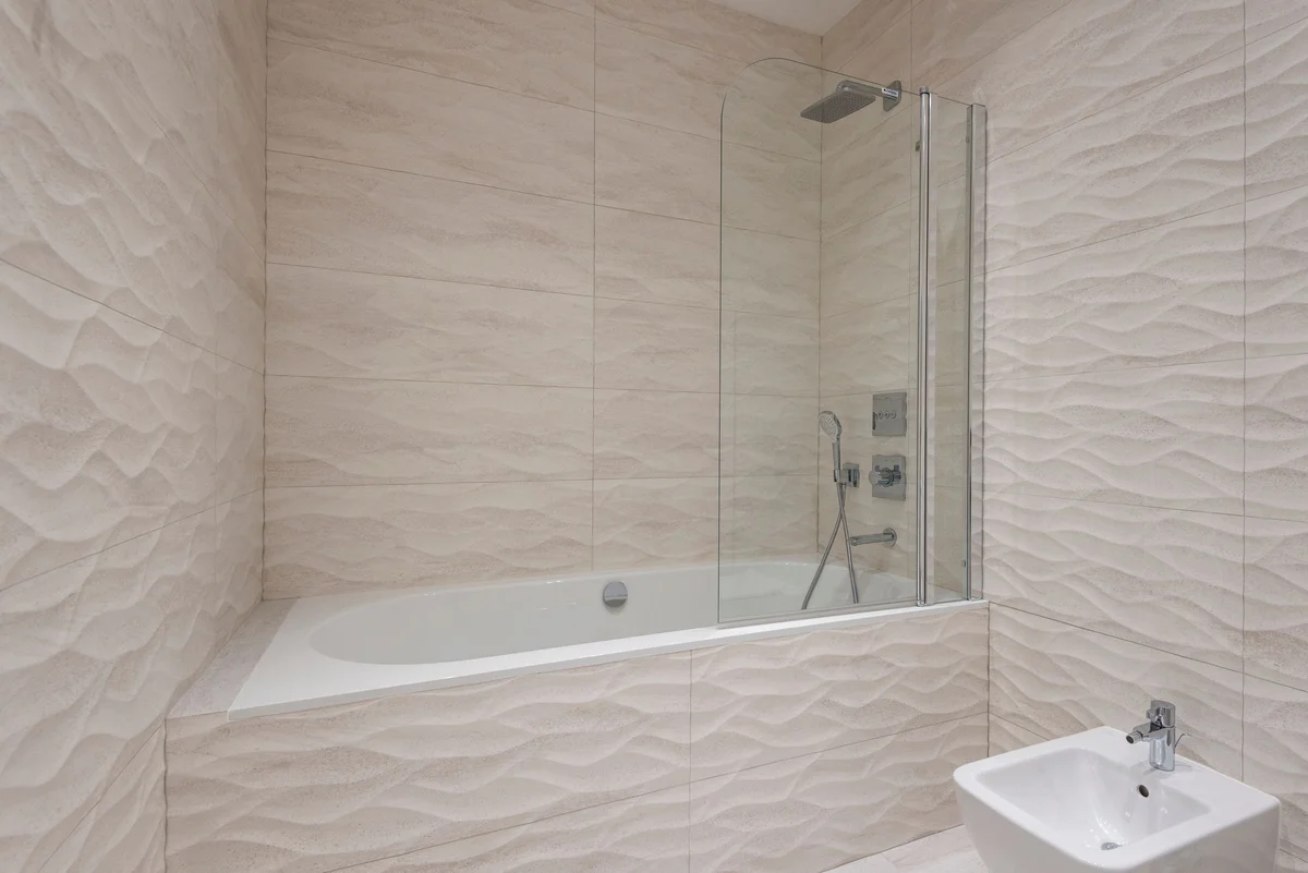 Sculptural cream wall tiles surrounding a bath